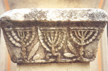 Το μαρμάρινο επίκρανο στο οποίο είναι χαραγμένες τρεις εβραϊκές λυχνίες